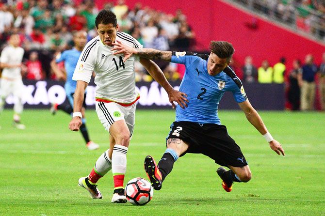 Mexico's Javier Hernandez (left) wins the ball during a challenge against Uruguay's Jose Gimenez