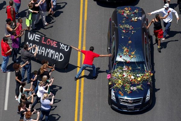 A banner stating "We Love You Mohammad" is displayed as well-wishers touch the hearse carrying the body of the late boxing champion Muhammad Ali on June 11