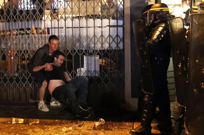 An English football fan tries to help his friend as French riot police encounter hundreds of drunken English football fans in Lille on Wednesday