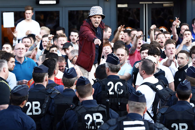 An English football fan gestures at police officers as supporters gather outside a pub in Lille on Wednesday