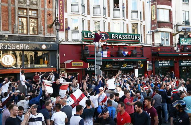 An England football fan climbs a road sign as supporters gather outside a pub in Lille on Wednesday