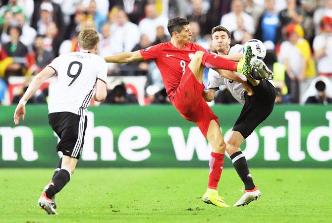 Poland's Robert Lewandowski (centre) and Germany's Jonas Hector (right) vie for possession