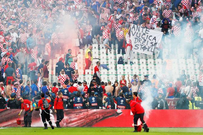 Stewards deal with flares that have been thrown onto the pitch