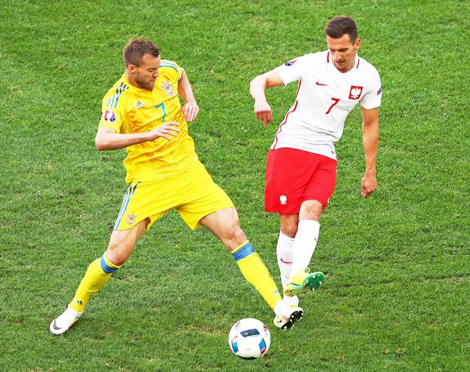 Ukraine's Andriy Yarmolenko (left) competes for the ball with Poland's Arkadiusz Milik