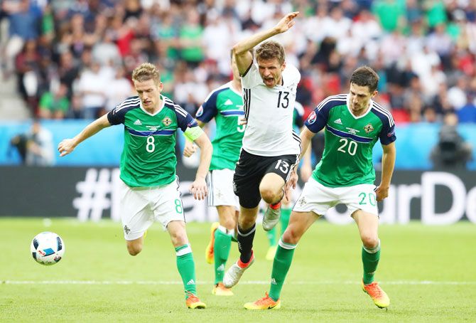 Germany's Thomas Mueller (centre) is challenegd by Northern Ireland's Steven Davis (left) and Craig Cathcart (right) 