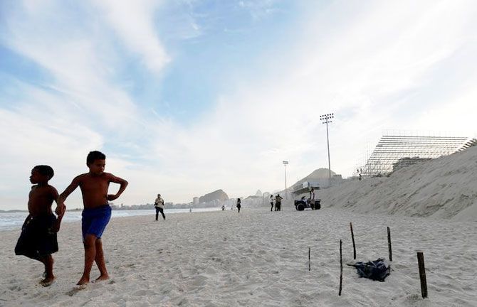 Children walks near a part of a mutilated body near the construction site of the beach volleyball venue for 2016 Rio Olympics on Copacabana beach in Rio de Janeiro, on Wednesday