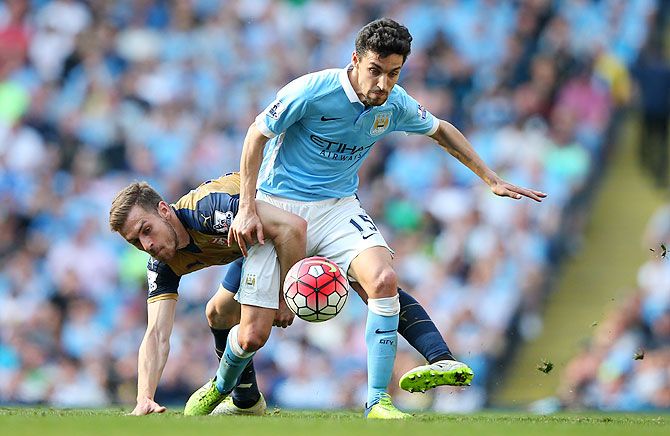 Manchester City's Jesus Navas holds off a challenge by Arsenal's Aaron Ramsey during their Barclays English Premier League match at the Etihad Stadium in Manchester on Sunday