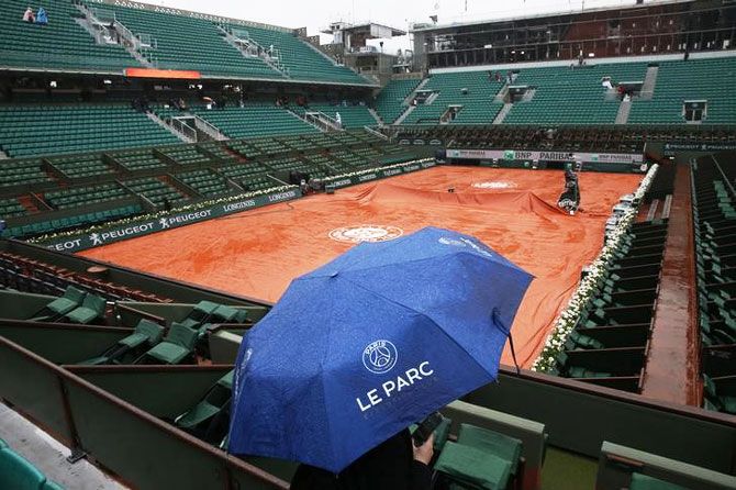 A spectator uses an umbrella at the central court as rain falls in Paris