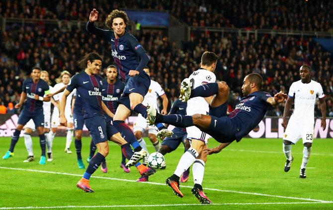 Basel's Andraz Sporar battles for the ball with PSG's Edinson Cavani and Lucas Moura