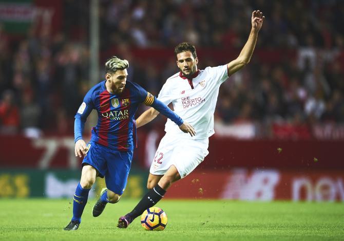 FC Barcelona's Lionel (left) run with the ball past Sevilla FC's Franco Vazquez during their La Liga match at Ramon Sanchez Pizjuan Stadium in Seville on Sunday