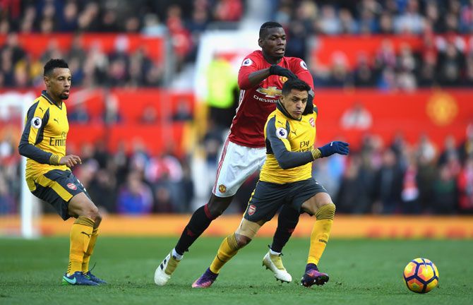 Arsenal's Alexis Sanchez (right) is pulled back by Manchester United's Paul Pogba (centre) as they vie for possession