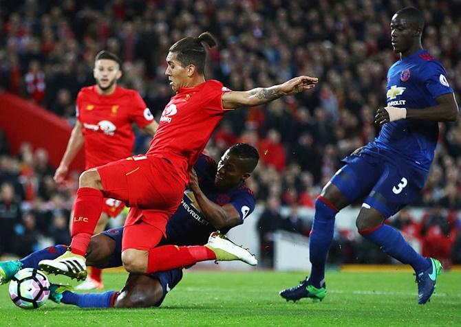 Antonio Valencia of Manchester United tackles Roberto Firmino of Liverpool 