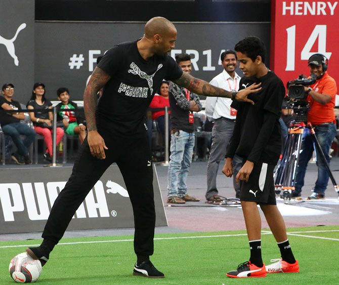 Thierry Henry 'challenges' a participant as he tries to win the ball during the training session