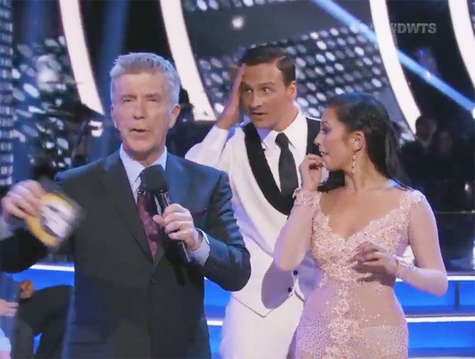 'Dancing with the Stars' host Tom Bergeron speaks a Ryan Lochte (2nd from left) wears a worried look as protestors step on the stage shouting Anti-Lochte slogans