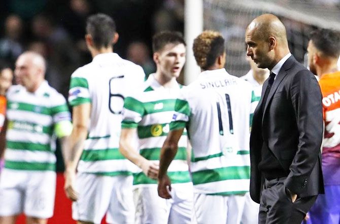 Manchester City manager Pep Guardiola looks dejected as Celtic players celebrate a goal