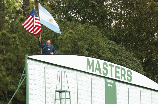 An Augusta National employee removes flags from the scoreboard at the first hole as a second weather warning and a tornado watch suspends play for the day during a practice round at The Masters at Augusta National GC. The suspension forced patrons to evacuate the course on Monday