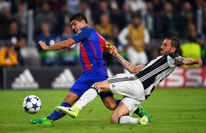 Barcelona's Luis Suarez shoots at goal under pressure from Juventus' Leonardo Bonucci