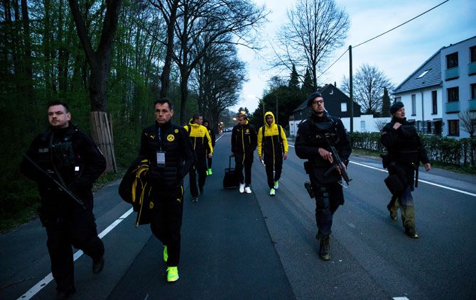 (Left-Right) Borussia Dortmund's Sven Bender, Marcel Schmelzer and Nuri Sahin are escorted to a car by police after the team bus of the Borussia Dortmund was damaged in an explosion in Dortmund, Germany, on Tuesday