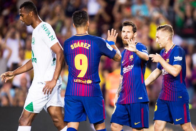 FC Barcelona's Lionel Messi celebrates with his teammates Luis Suarez (left) and Gerard Deulofeu (right) after scoring his team's third goal