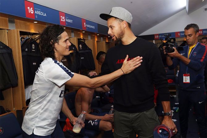 NBA Star Stephen Curry greets PSG's Edinson Cavani in the dressing room after their victory over St Etienne at Parc Des Princes stadium in Paris on Friday