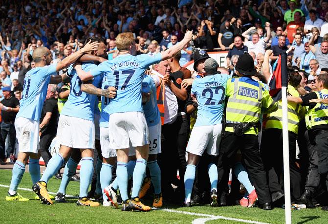 Stewards control the crowds after fans spill onto the field as Sterling celebrates the winning goal