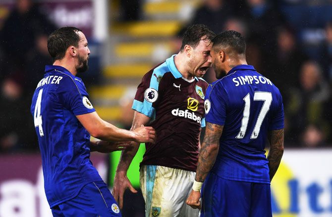 Burnley's Ashley Barnes and Leicester City's Danny Simpson square off while Leicester's Danny Drinkwater tries to separate them during their Premier League match at Turf Moor in Burnley, on Tuesday