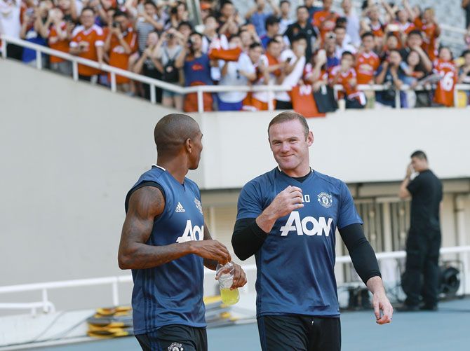 Frenzied fans click pictures (blurred background) of Manchester United's Ashley Young and Wayne Rooney during the team training session at their pre-season tour of China at Shanghai Stadium in Shanghai on July 21, 2016