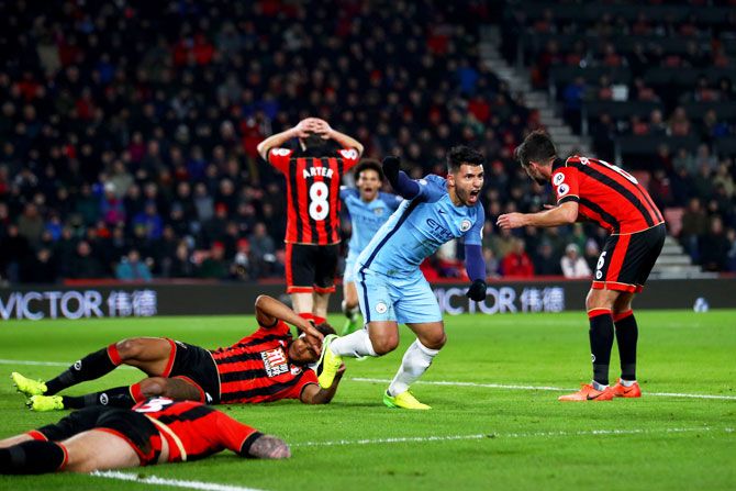 Manchester City's Sergio Aguero celebrates after sliding in a goal next to Bournemouth's Tyrone Mings to score his team's second goal during their Premier League match at Vitality Stadium in Bournemouth on Monday