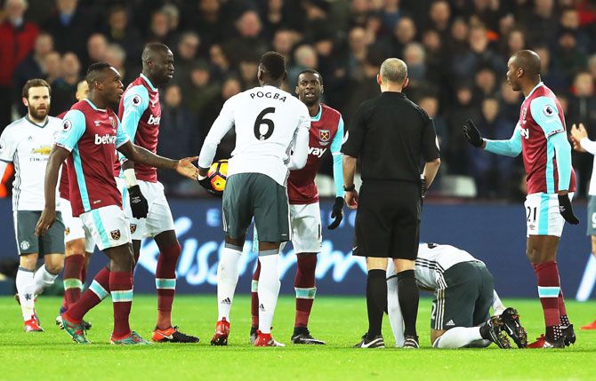 Referee Mike Dean is confronted by West Ham players