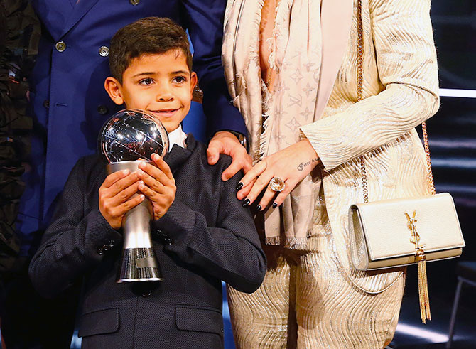 Cristiano Ronaldo Jr, Ronaldo's son, poses with his father's award. Photograph: Ruben Sprich/Reuters