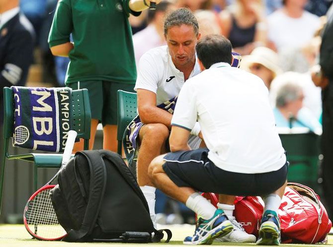 Ukraine’s Alexandr Dolgopolov receives medical attention before having to retire from his first round match against Switzerland’s Roger Federer during the Wimbledon Championships on Tuesday
