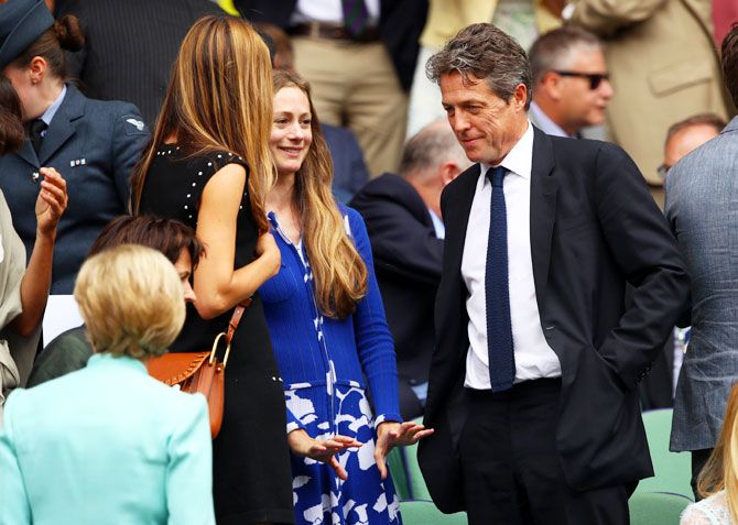Hugh Grant speaks to fellow guests at the centre court royal box prior to the men's singles final between Roger Federer and Marin Cilic on Sunday