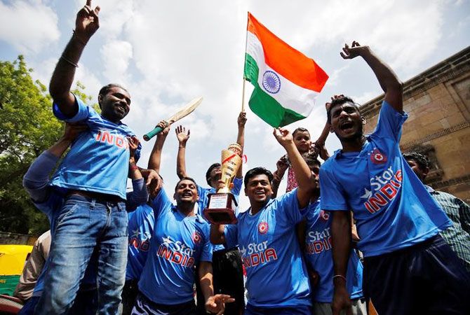 Indian cricket fans in Ahmedabad, hold a trophy as they cheer for their team before the start of the Champions Trophy final between India and Pakistan at the Oval