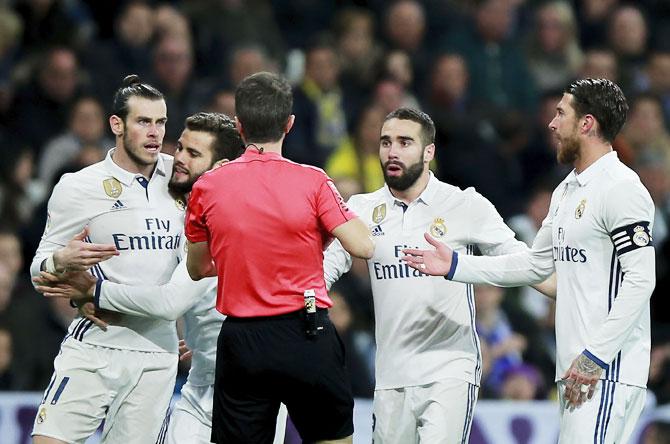 Real Madrid's Nacho Fernandez restrains Gareth Bale (left) as referee David Fernandez Borbalan shows the latter the red card as teammates Daniel Carvajal (2ndR) and Sergio Ramos (R) look on in disbelief during the La Liga match against UD Las Palmas at Estadio Santiago Bernabeu in Madrid, on Wednesday