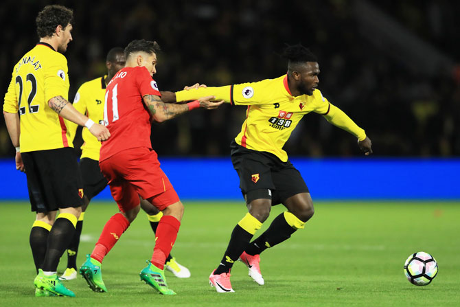 Watford's Isaac Success is held back by Liverpool's Roberto Firmino as they vie for possession
