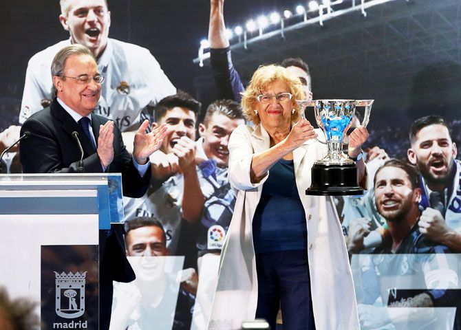 Madrid Mayor Manuela Carmena holds up a replica of the La Liga trophy as Real Madrid president Florentino Perez applauds during a ceremony at the Town Hall in Madrid on Monday