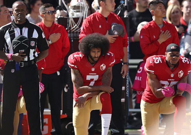 Eric Reid, right, and Colin Kaepernick, centre, of the San Francisco 49ers kneel in protest of racism during the national anthem prior to their NFL game on September 27 last year