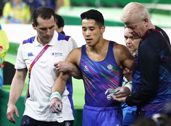 Scotland’s injured Kelvin Cham is given assistance after he competes on the rings in the Men's Team Final and Individual Qualification during the Artistic Gymnastics at Coomera Indoor Sports Centre