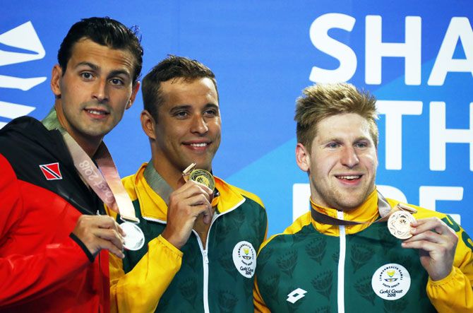 Gold medalist Chad Le Clos of South Africa (centre), silver medalist Dylan Carter of Trinidad and Tobago and bronze medalist Ryan Coetzee of South Africa pose on the podium after the Men's 500m Butterfly final at Optus Aquatic Centre in Gold Coast, Australia on Friday