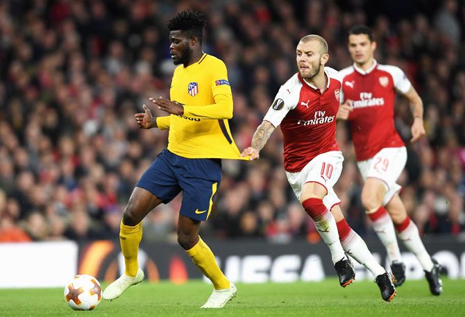 Atletico Madrid's Thomas Partey is pulled back by Arsenal's Jack Wilshere