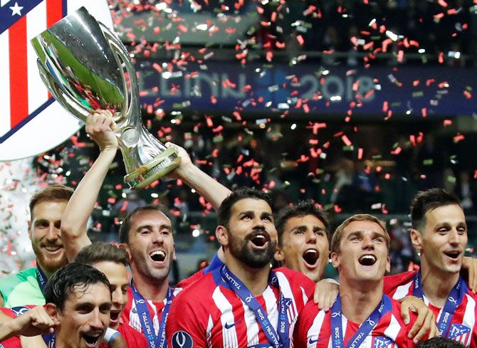 Atletico Madrid's Diego Godin lifts the trophy and celebrates with teammates after winning the Super Cup in Madrid on Wednesday