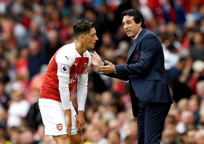 Arsenal's Mesut Ozil speaks with coach Unai Emery