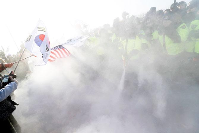 Police try to extinguish burnt portraits of North Korean leader Kim Jong Un during an anti-North Korea protest before the opening ceremony for the Pyeongchang 2018 Winter Olympics in Pyeongchang, South Korea, on Friday