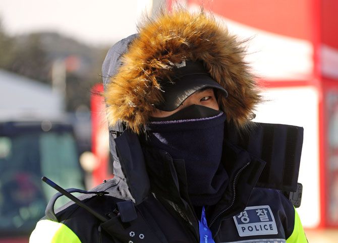 A police officer protects his face from the cold at the Olympic stadium at the Pyeongchang Olympic Games on Feb 7