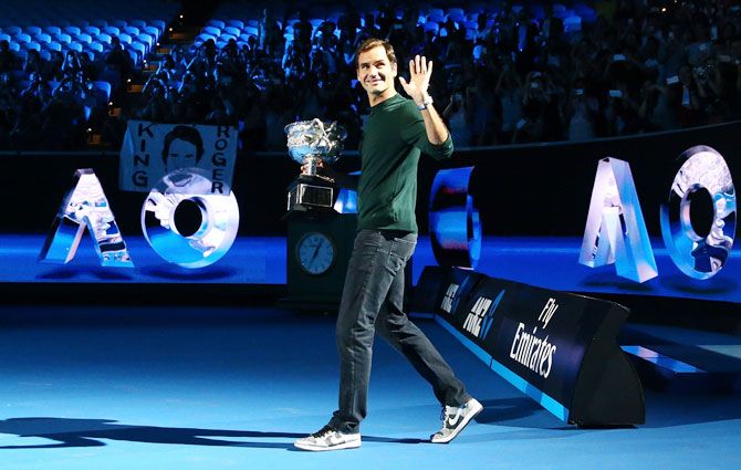 Switzerland's Roger Federer arrives on court with the Norman Brookes trophy at the Australian Open official draw at Melbourne Park on Thursday