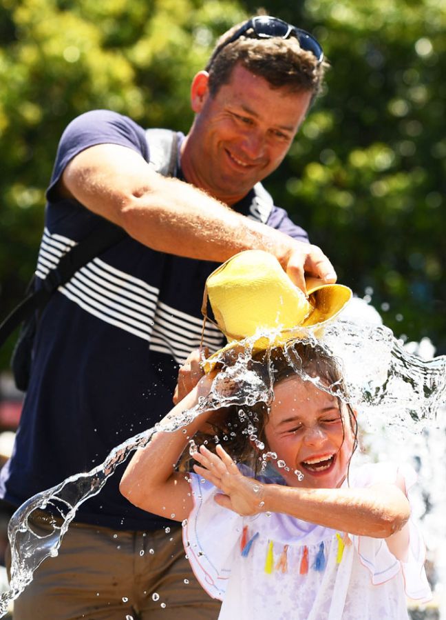 A father helps his daughter cool down the fun way at Melbourne Park on Friday