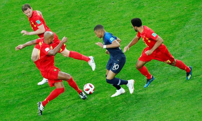 France's Kylian Mbappe is challenged by Belgium's Vincent Kompany and Mousa Dembele