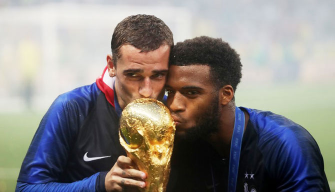 France's Antoine Griezmann and teammate Thomas Lemar kiss the trophy as they celebrate their World Cup win