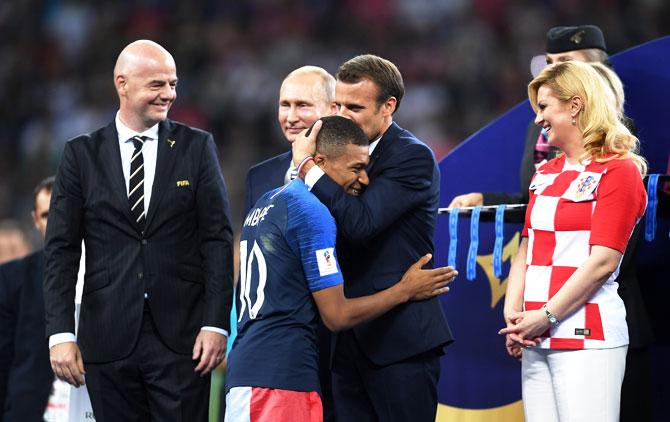 French President Emmanuel Macron awards Kylian Mbappe of France with the FIFA Young Player Award as President of Russia Vladimir Putin and President of Croatia, Kolinda Grabar Kitarovic look on following the 2018 FIFA World Cup final between France and Croatia at Luzhniki Stadium in Moscow, Russia, on Sunday