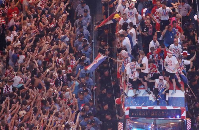 Croatia team players atop a bus celebrate with fans during the parade